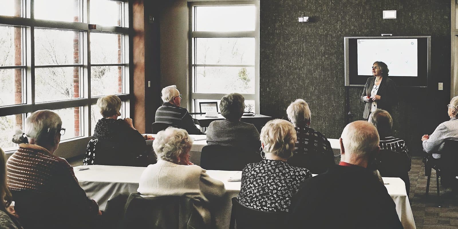 A presenter speaking to an audience at a Medicare 101 seminar in a classroom setting